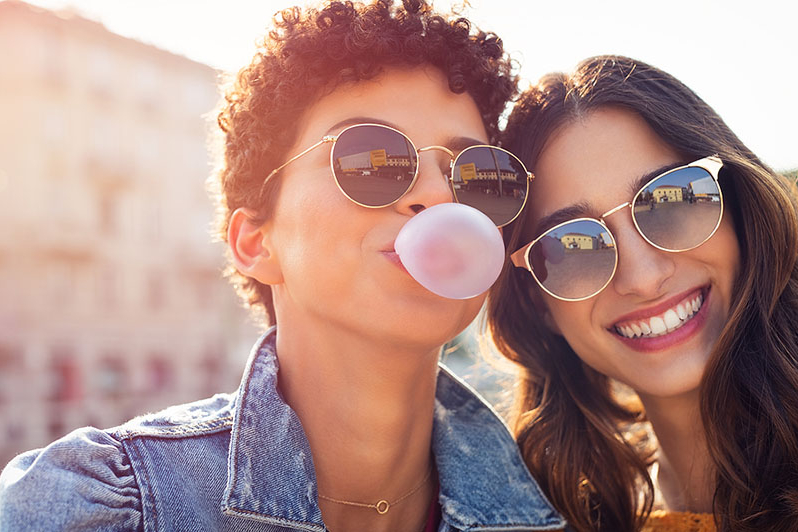 Two women chewing gum with good oral health habits